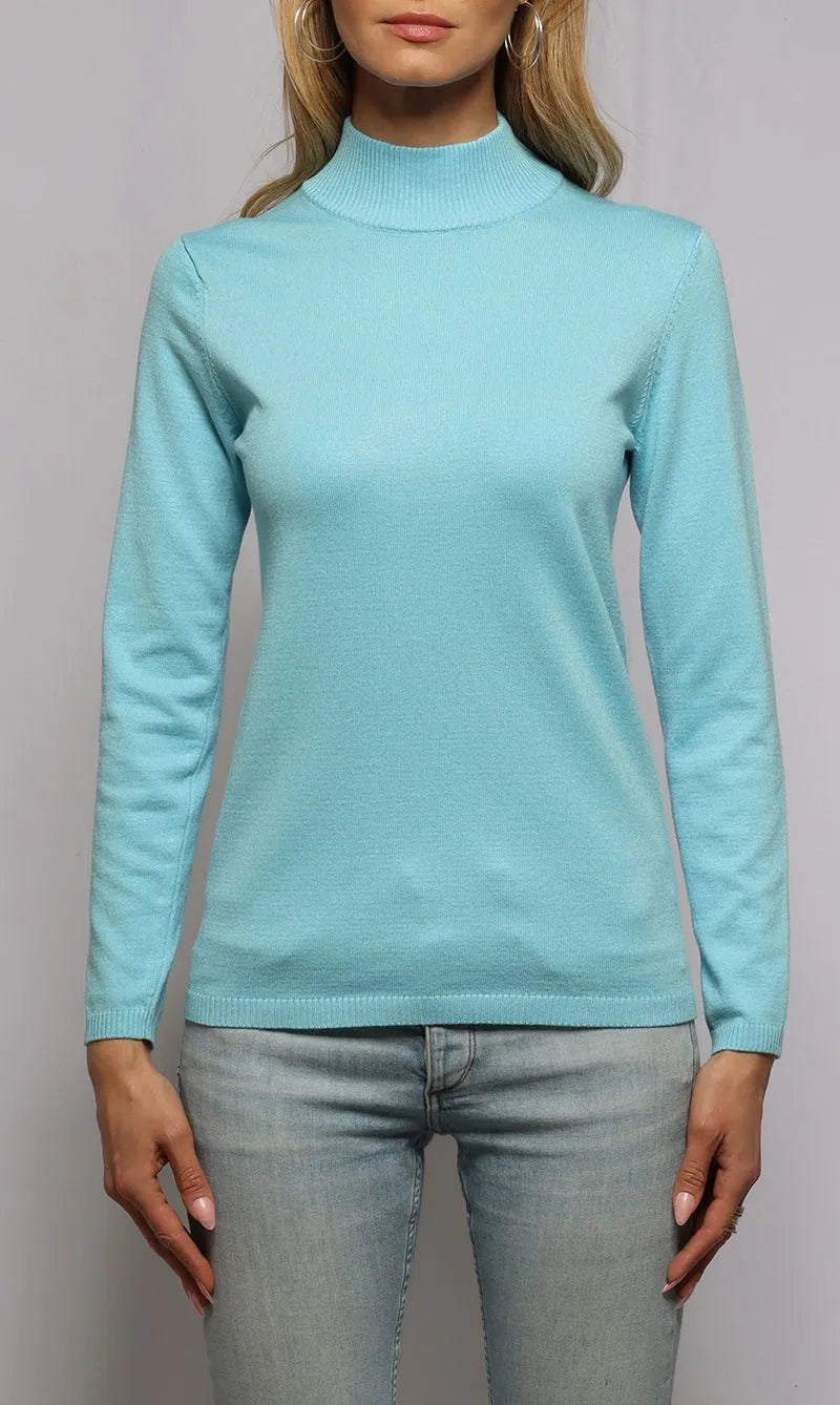 Person wearing a light blue turtleneck sweater and jeans on a plain background