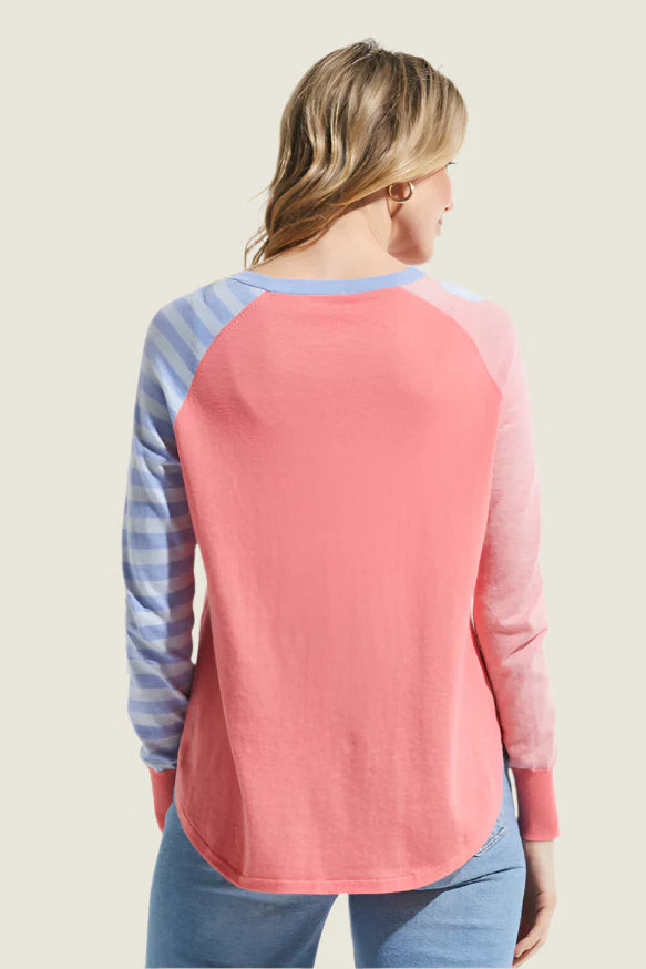 Woman wearing a pink and blue striped long-sleeve top on a beige background