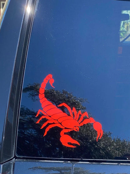 Red scorpion decal on a black car window