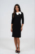 A woman modeling a black knee-length dress with three-quarter sleeves and a contrasting white bow collar