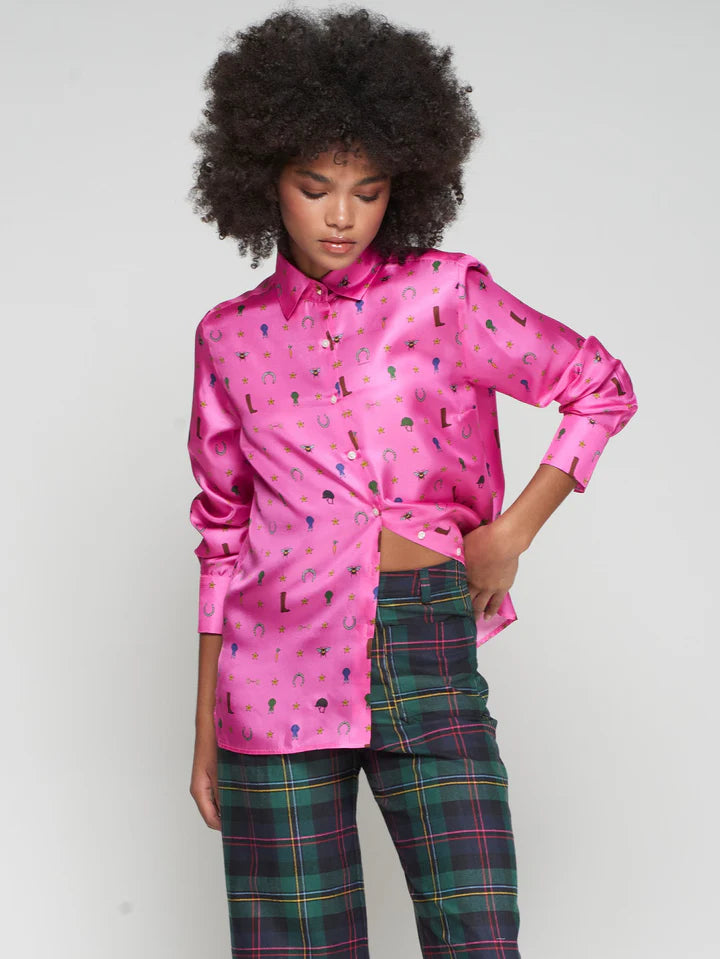 Person wearing a bright pink shirt with a equestrian pattern and plaid pants on a plain background