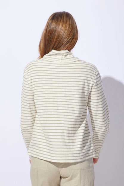 The back of a woman wearing a striped sweater and pants on a plain background