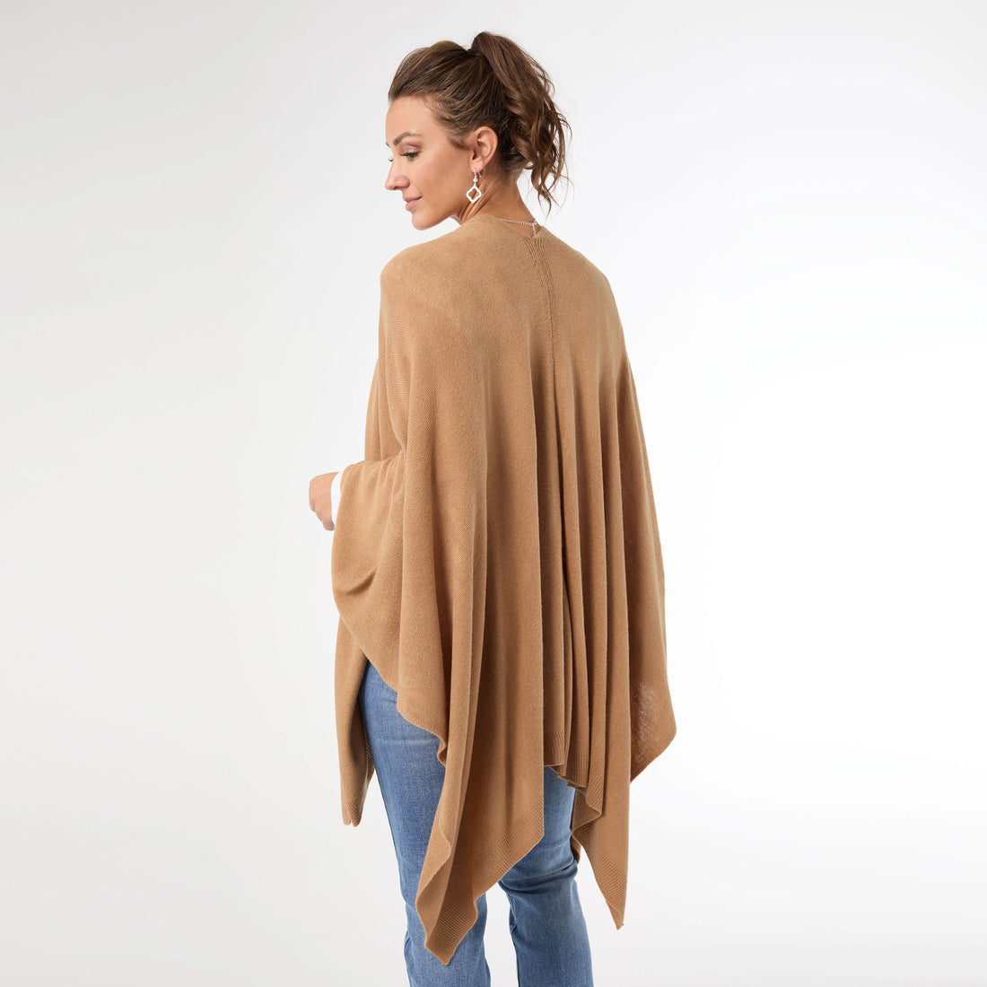 Woman wearing a beige poncho over a white background