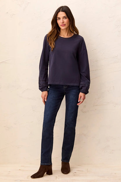 A woman wearing a dark navy blue long-sleeve top with decorative eyelet lace detailing at the neckline and cuffs by tribal Cotton Slub Eyelet Trim Long Sleeve Knit Top