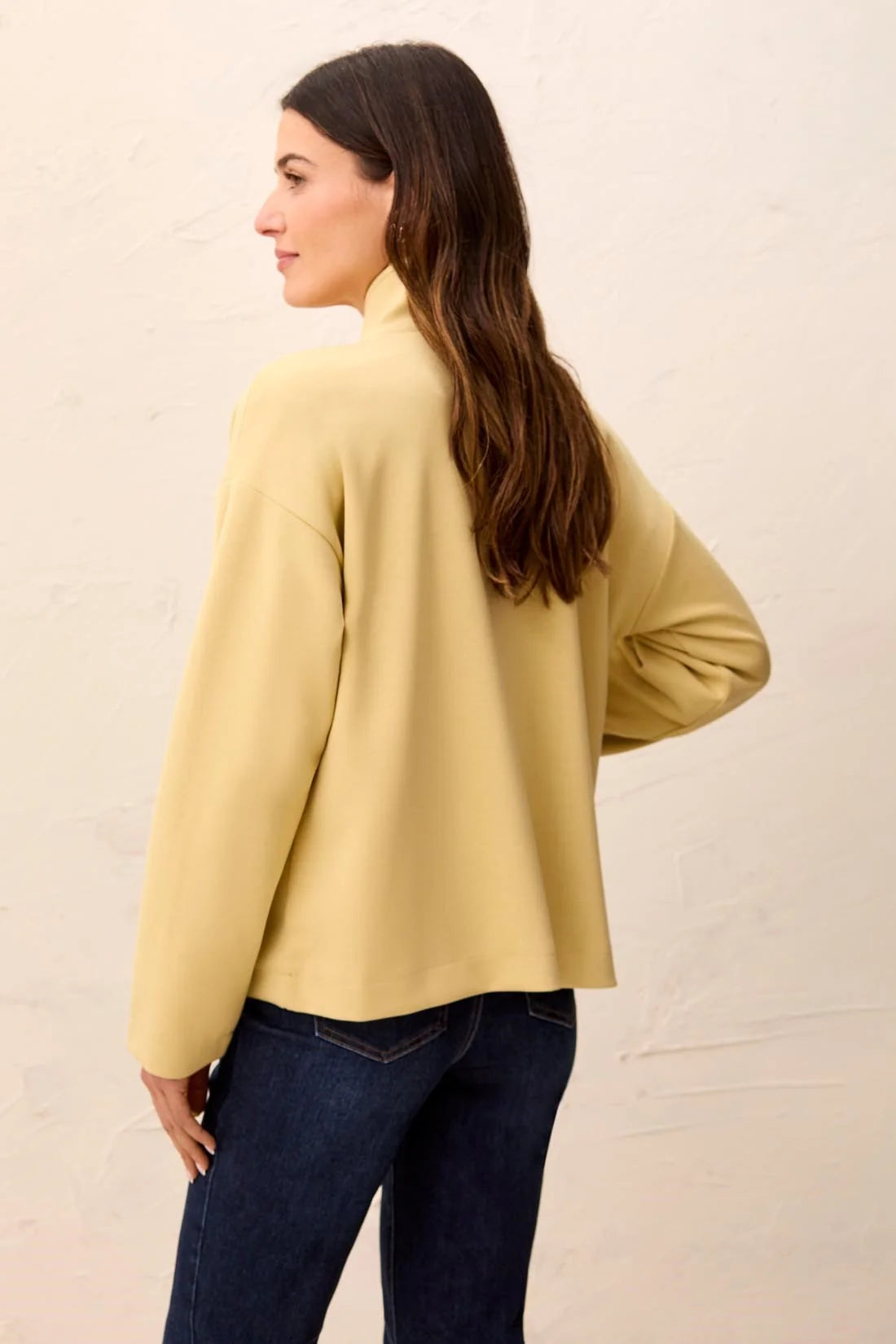A woman wearing a pale yellow long-sleeve mock neck top tribal Soft-Touch Zip-Up Funnel Neck Utility Jacket in the color light pear