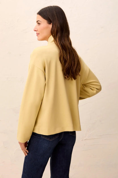 A woman wearing a pale yellow long-sleeve mock neck top tribal Soft-Touch Zip-Up Funnel Neck Utility Jacket in the color light pear