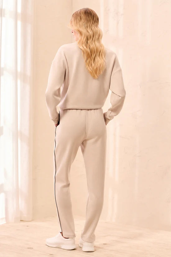 A woman modeling straight-leg pants, featuring thin black side stripes by tribal TECHNO LUX Jogger Pants With Contrast Piping And U-Hem