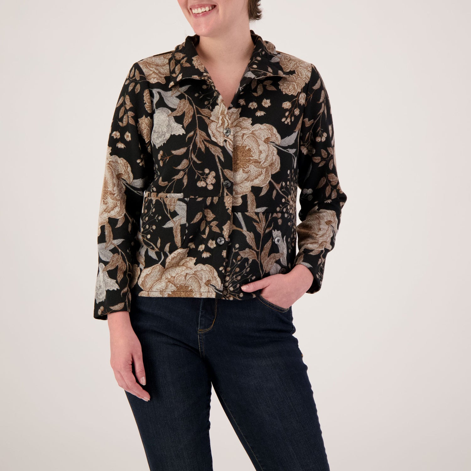 Person wearing a floral patterned shirt with long sleeves on a plain background