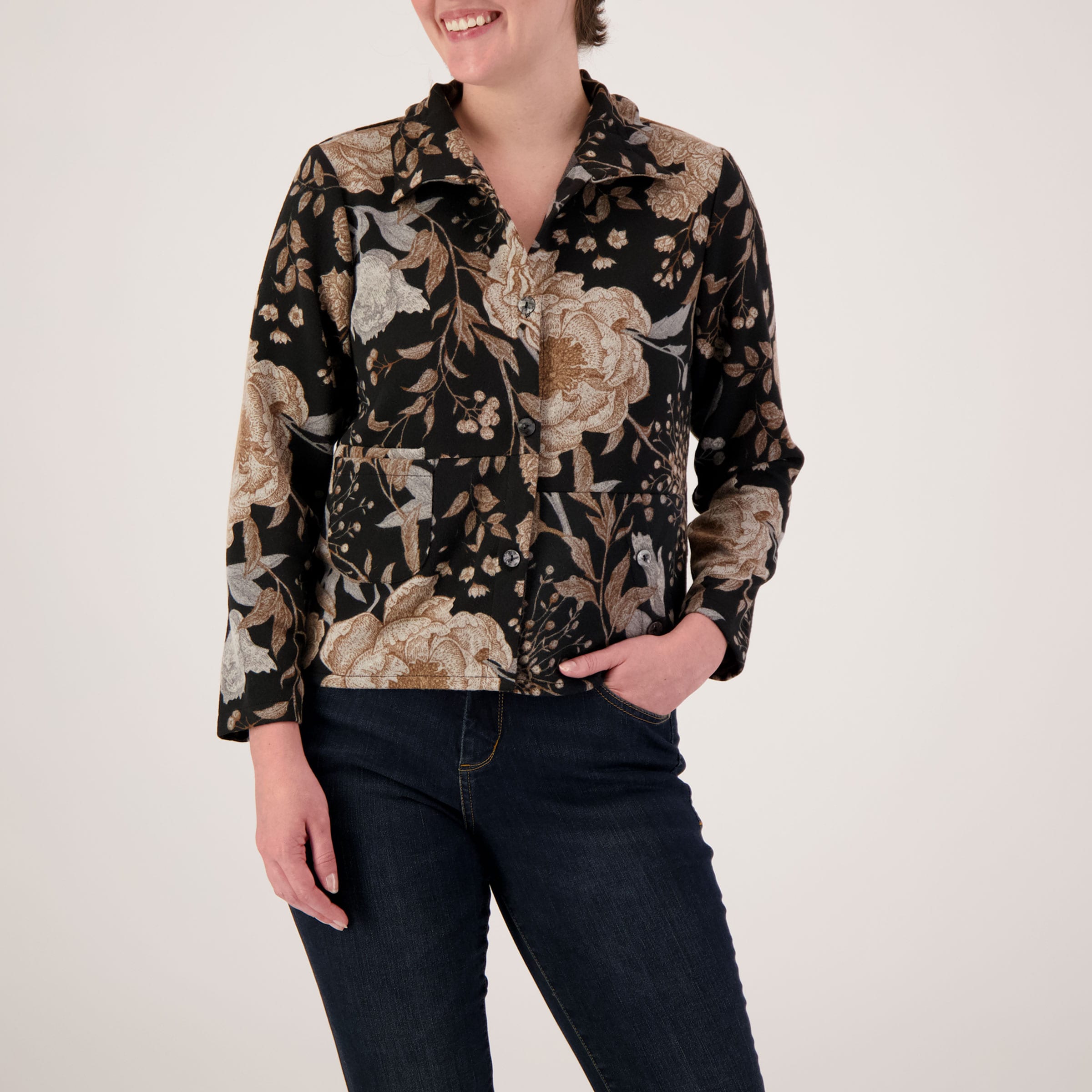 Person wearing a floral patterned shirt with long sleeves on a plain background